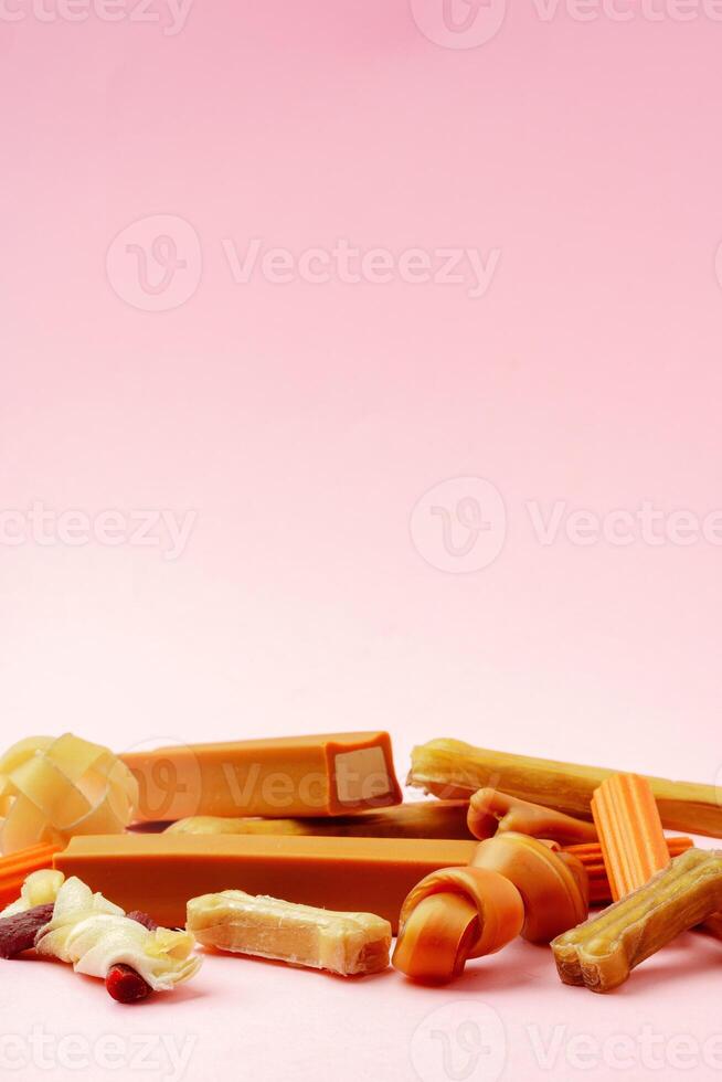 Dog chew bone and sticks on pink background photo