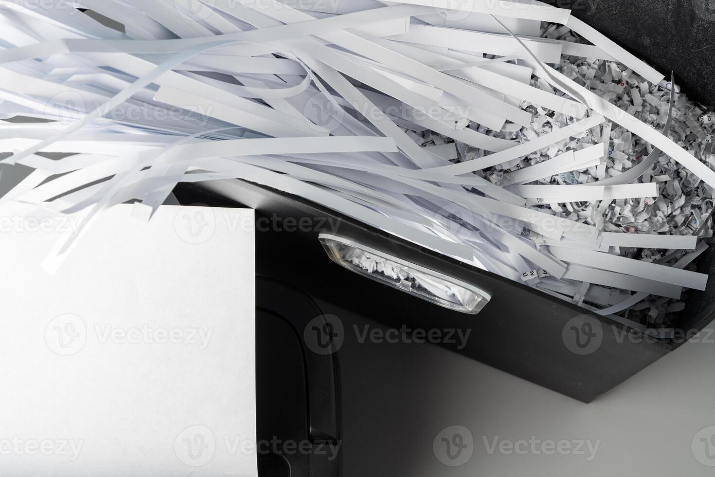 Black paper shredder cutting paper on gray background photo
