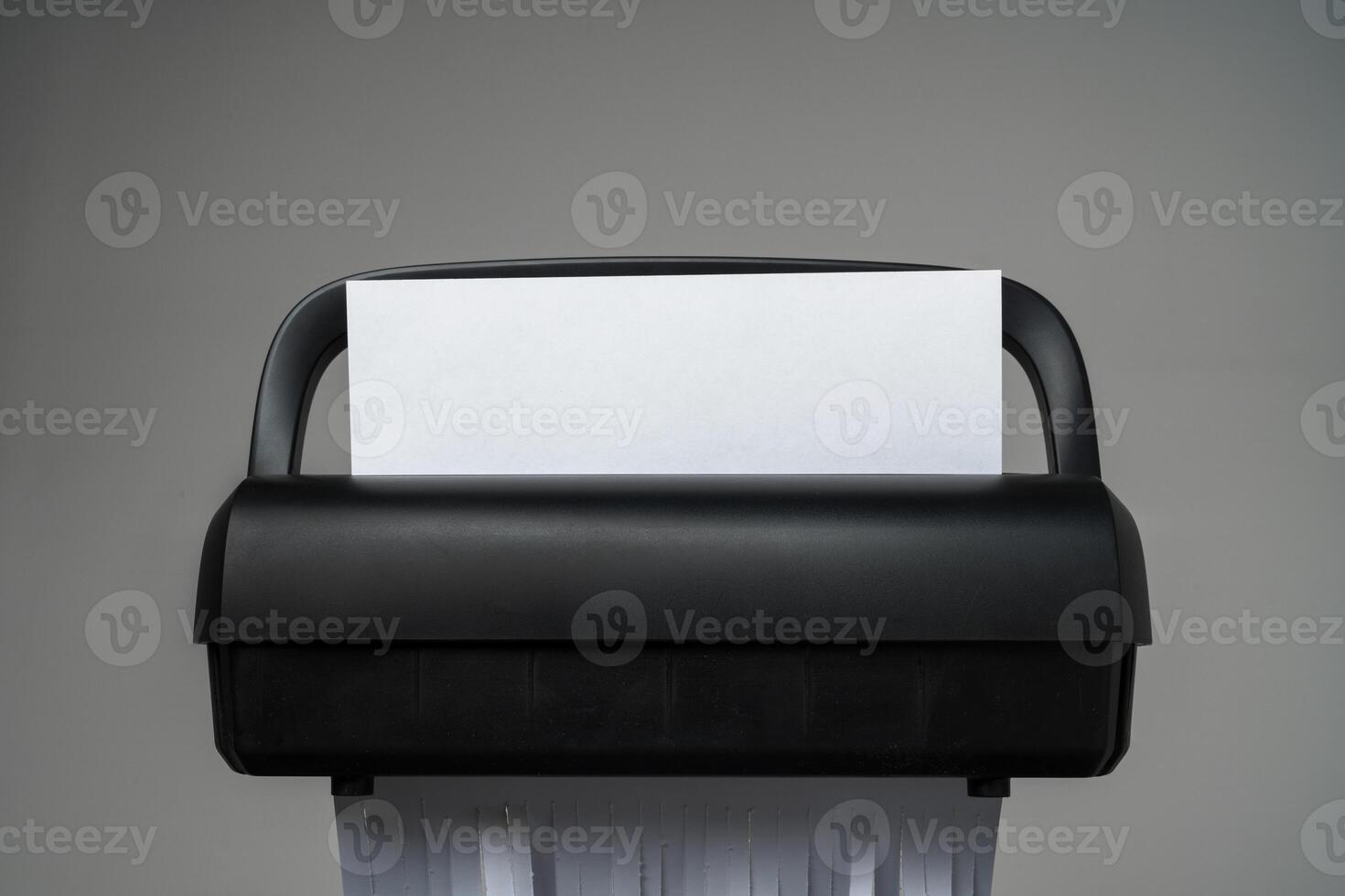 Black paper shredder cutting paper on gray background photo