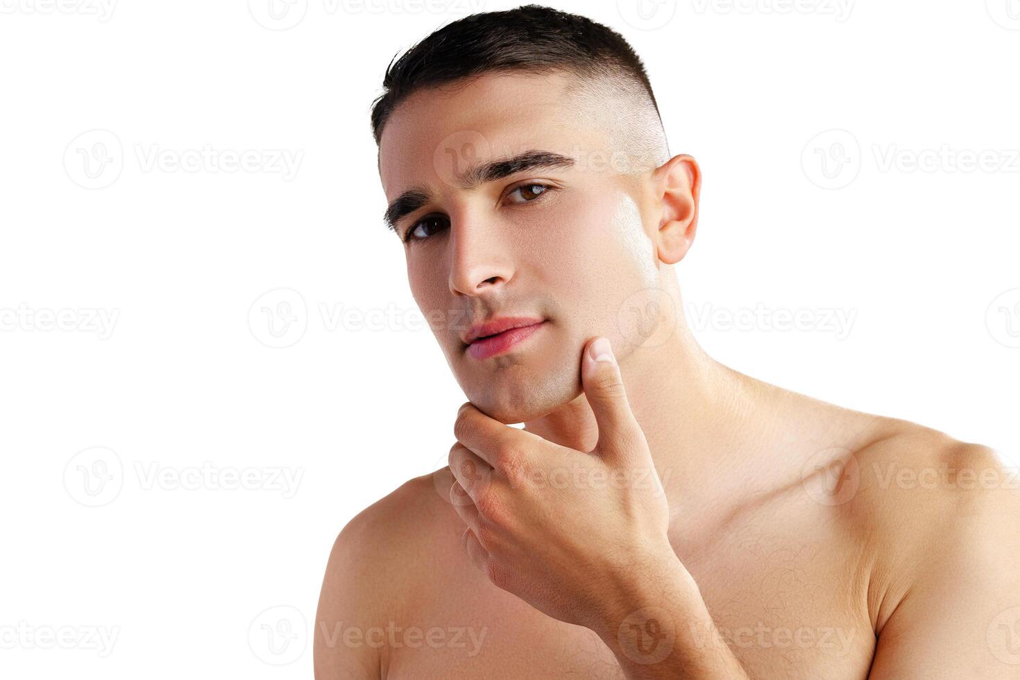 Young attractive brunet guy with perfect skin touching chin on white background photo