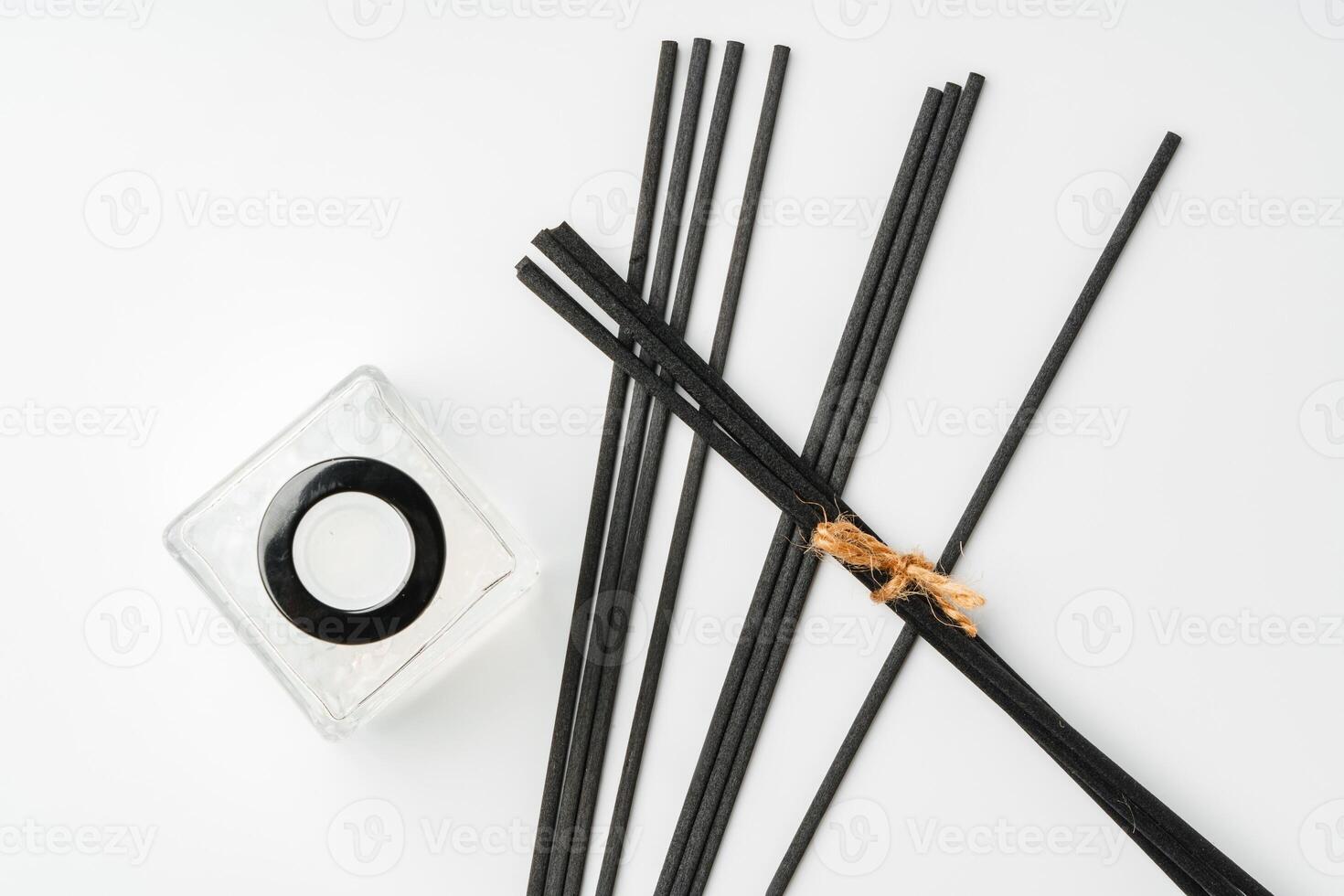 A minimalist display of essential oil and black diffuser sticks on a clean white background photo