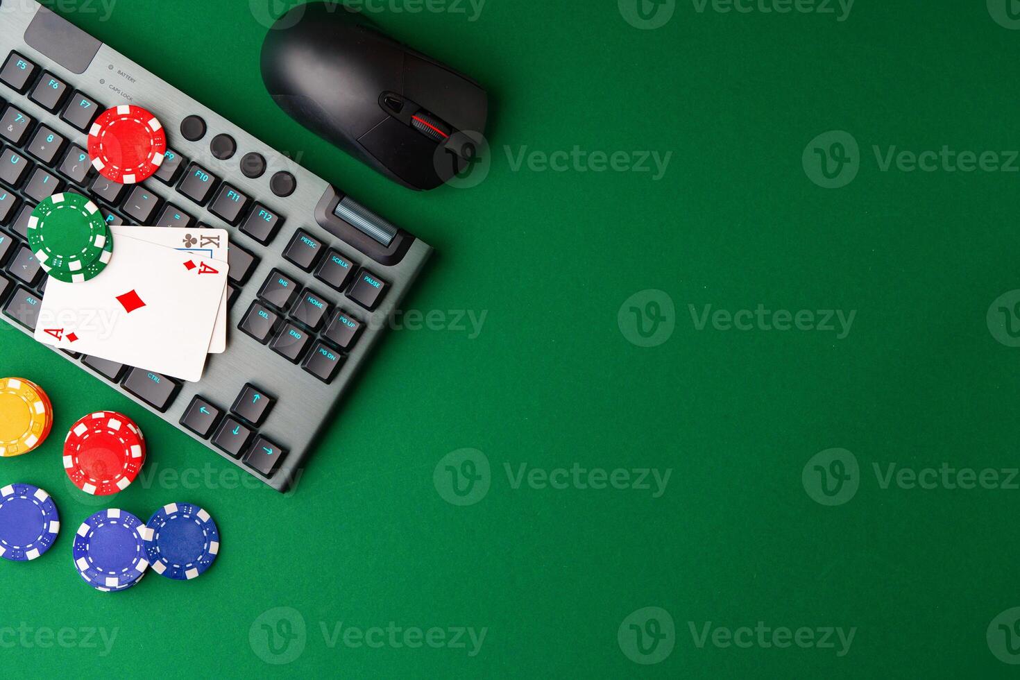 Chips and playing cards on a green felt surface near a computer keyboard during an online gaming session at home photo