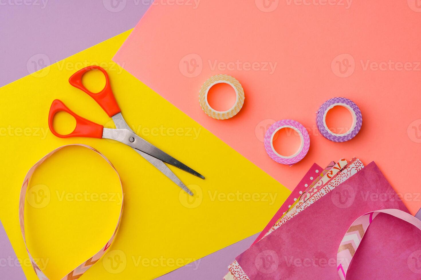 Scissors and decorative tape on colorful craft paper in a bright workspace photo