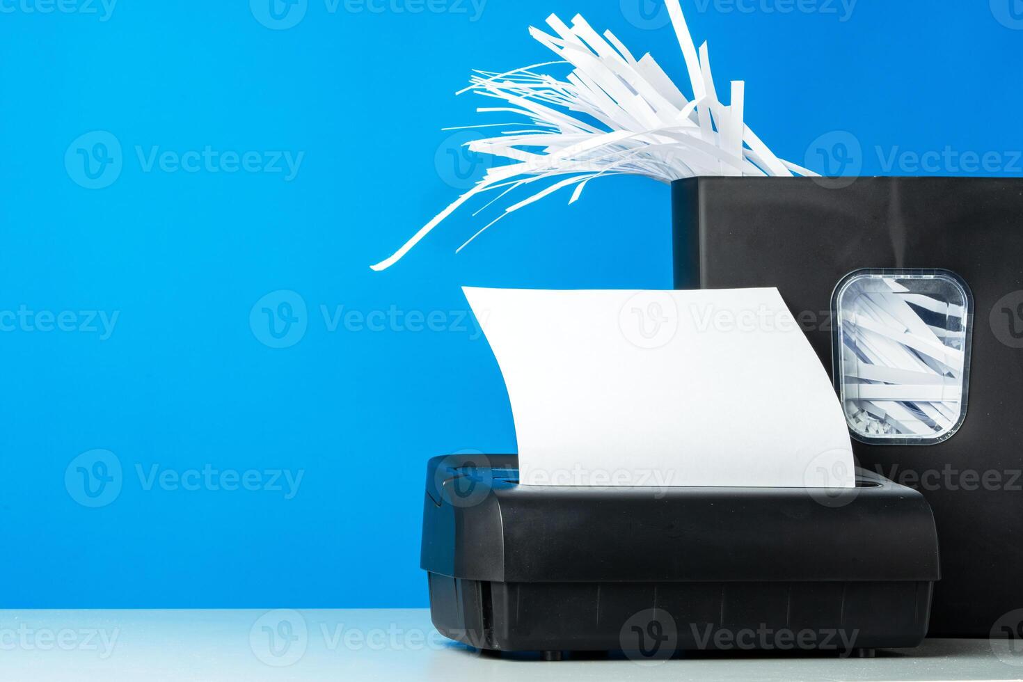 Office paper shredder on blue studio background photo
