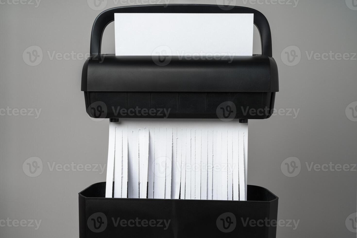 Black paper shredder cutting paper on gray background photo