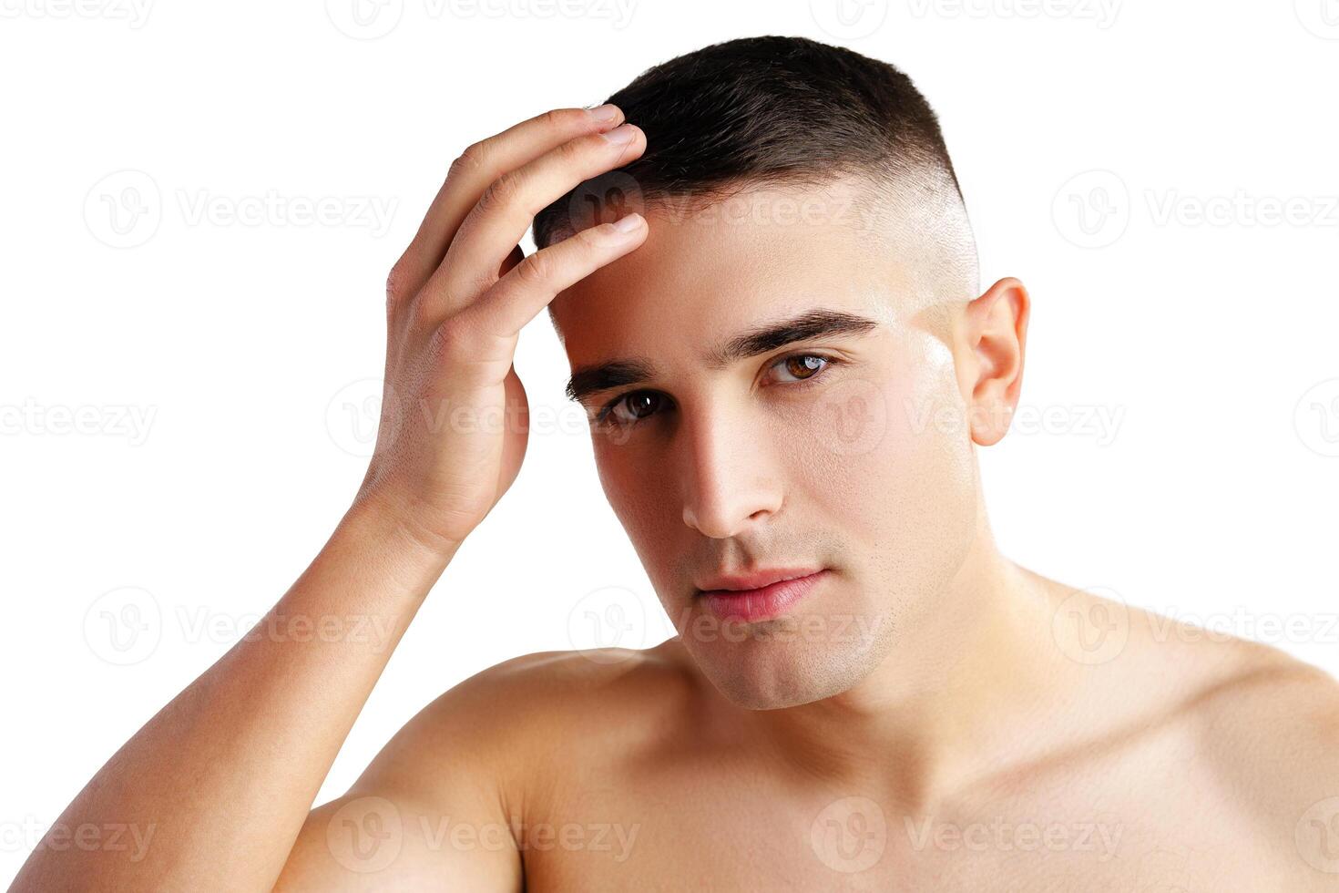 Young man standing shirtless and touching his face with hands photo