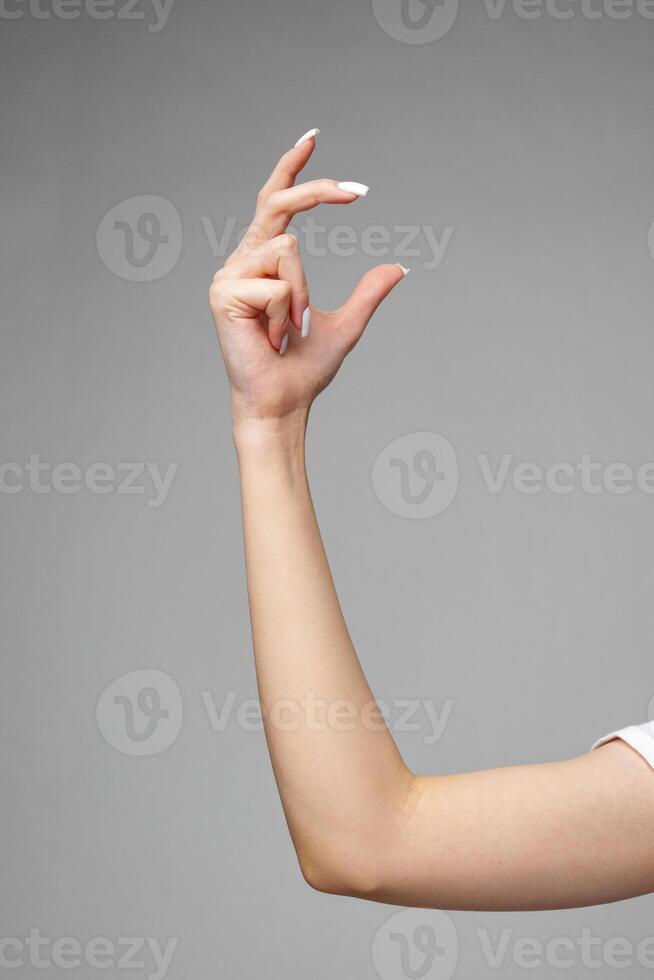 Female hand gesturing sign against gray background photo