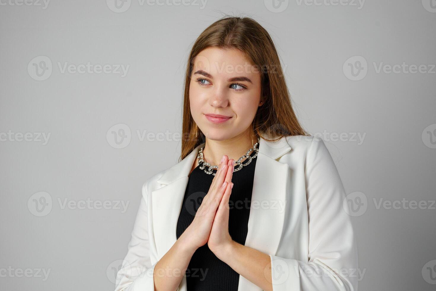 Thoughtful Young Woman in a Stylish White Blazer Posing on gray background photo