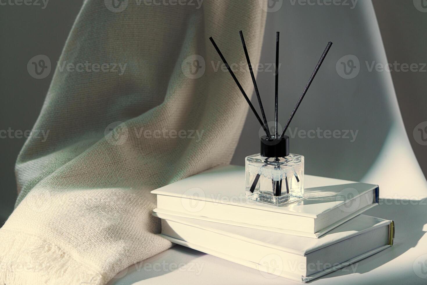 Liquid home perfume in glass diffuser with sticks on chair photo