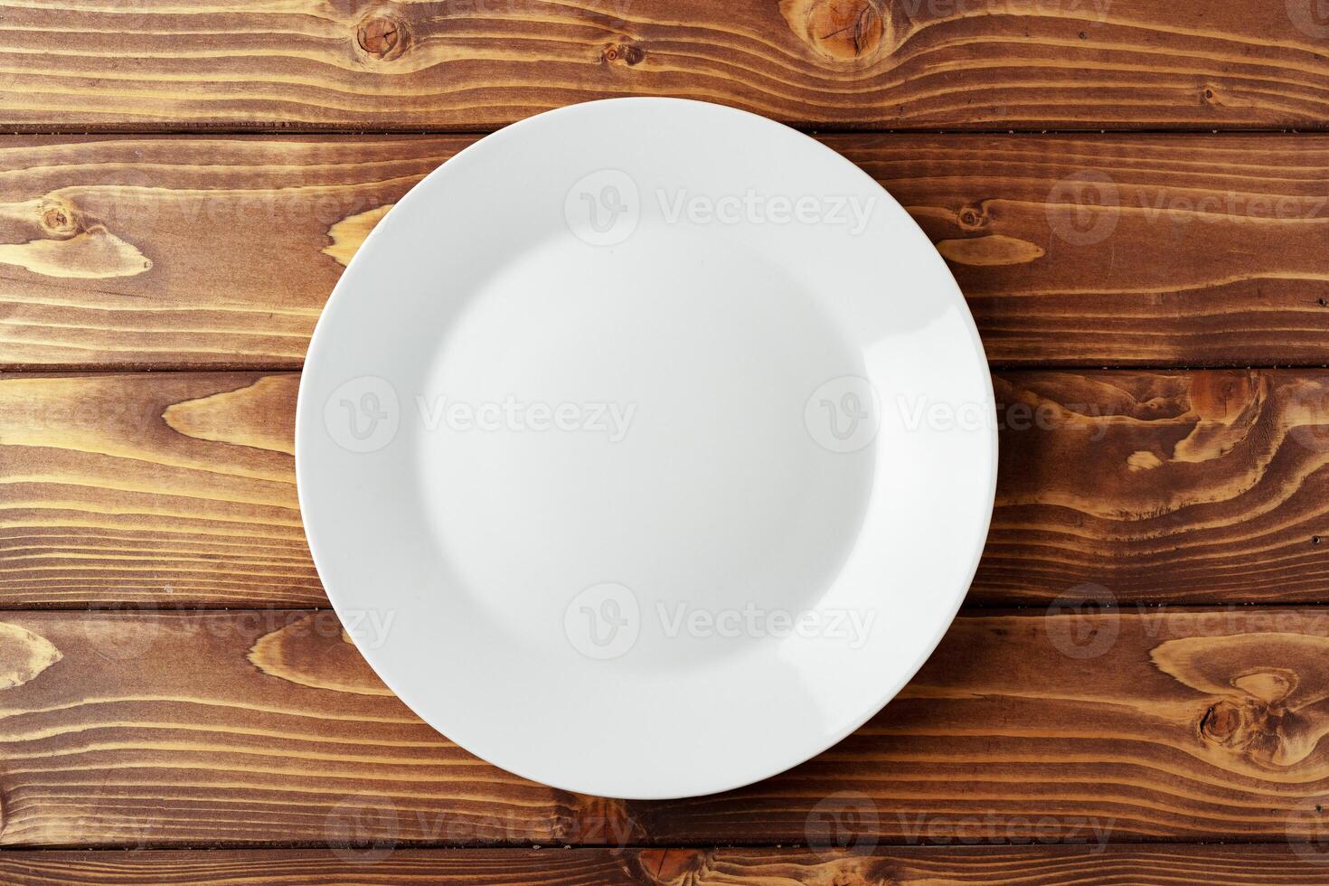 White ceramic plate on wooden background top view photo
