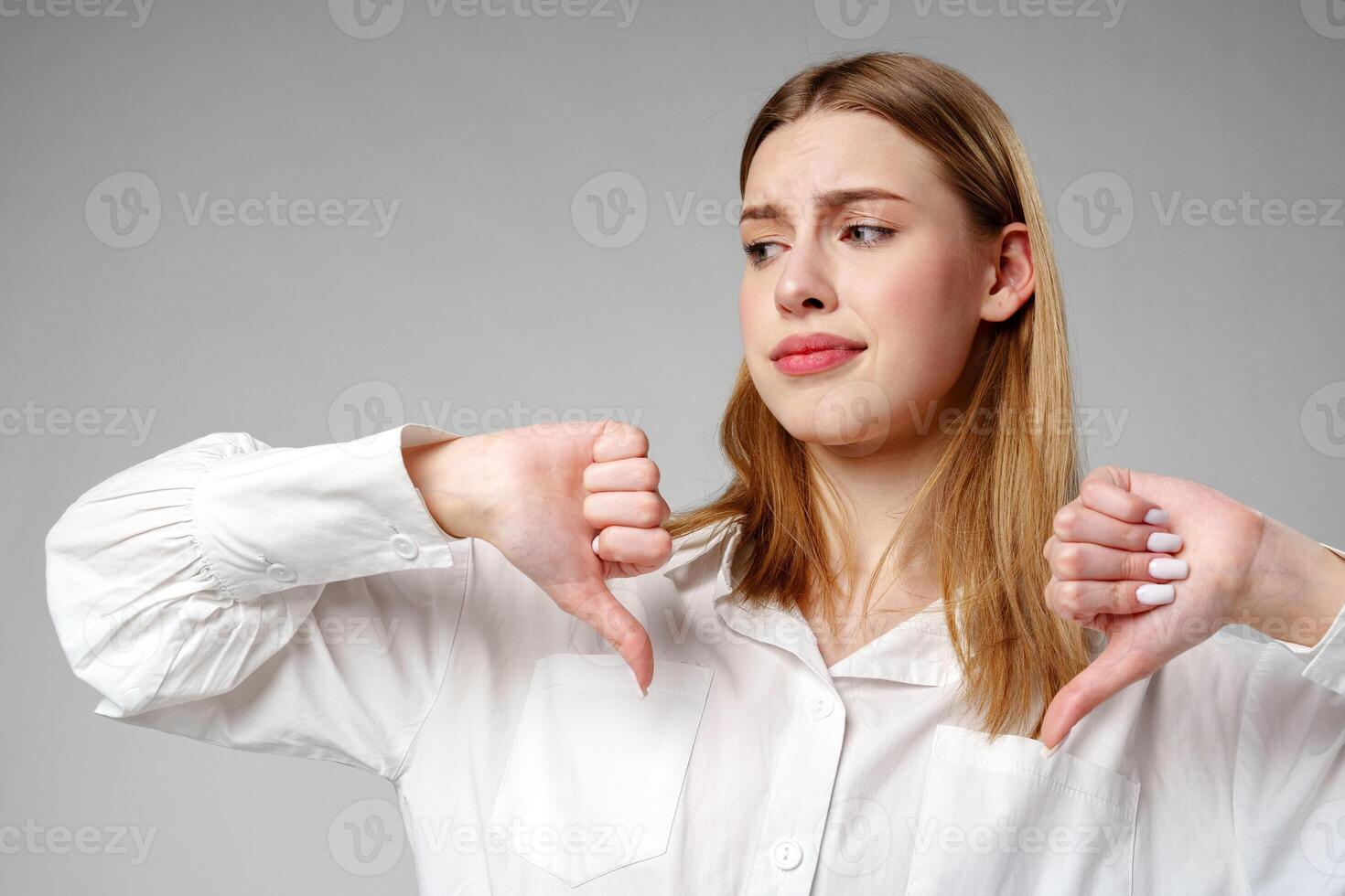 Young Woman in White Shirt Pointing Finger Down Dislike photo