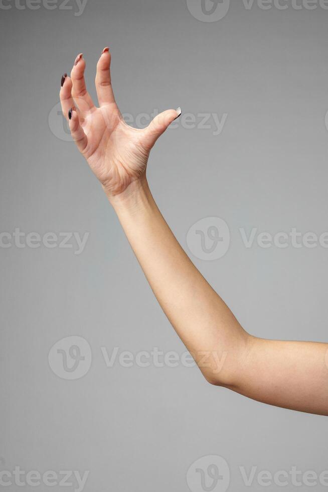 Outstretched Bare Arm With a Relaxed Hand Against a Gray Background photo