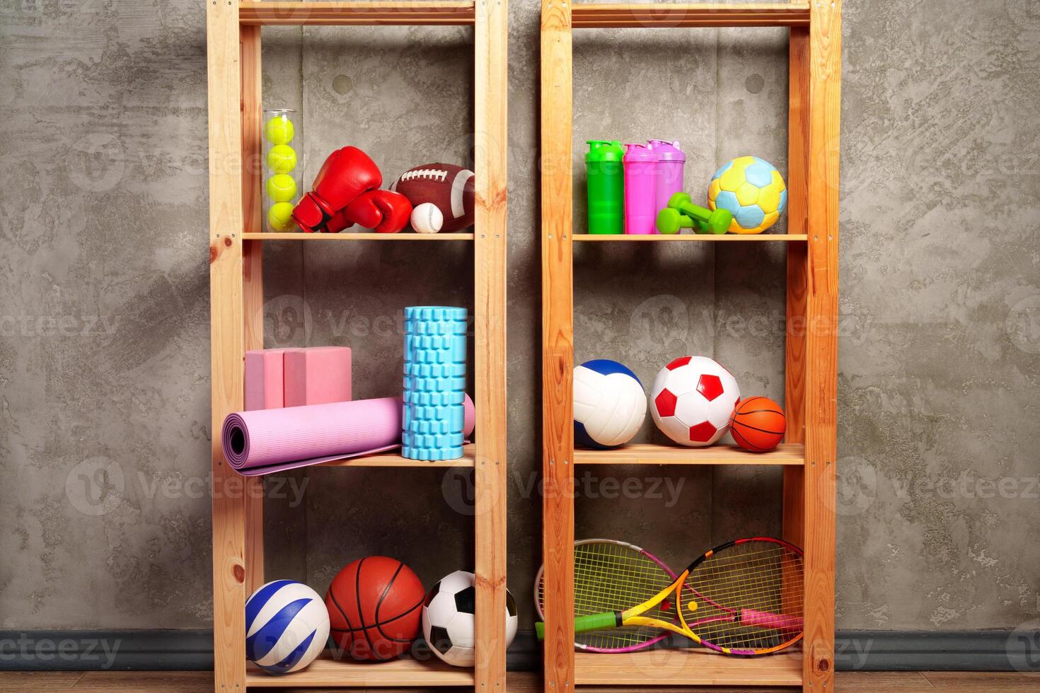 Shelves with different sports equipment against green wall photo