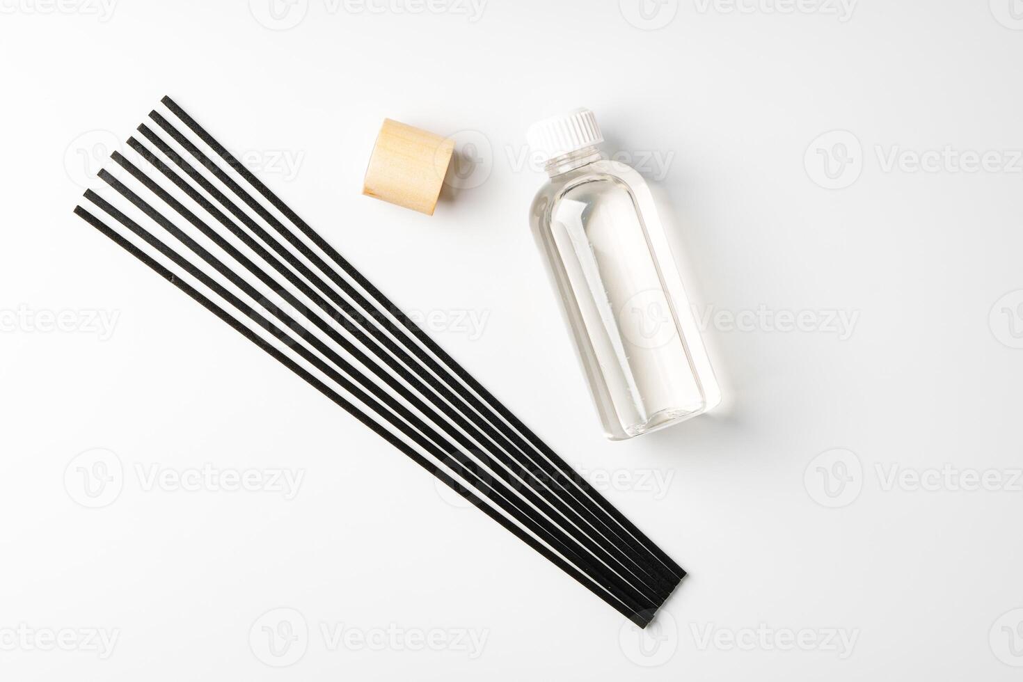A minimalist display of essential oil and black diffuser sticks on a clean white background photo