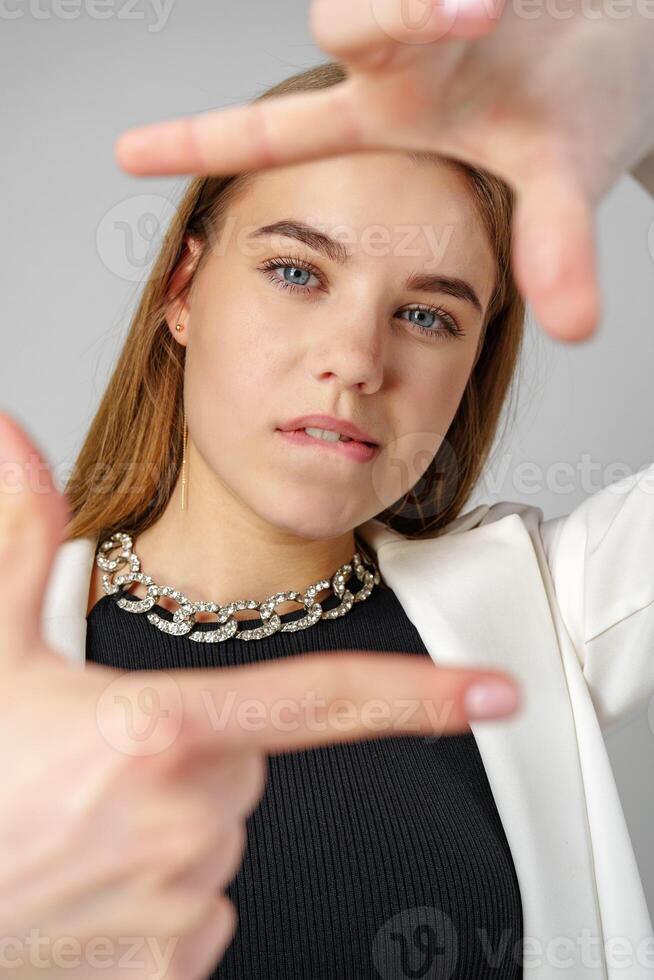 Young Woman Making Frame Gesture With Hands Against a Neutral Background photo