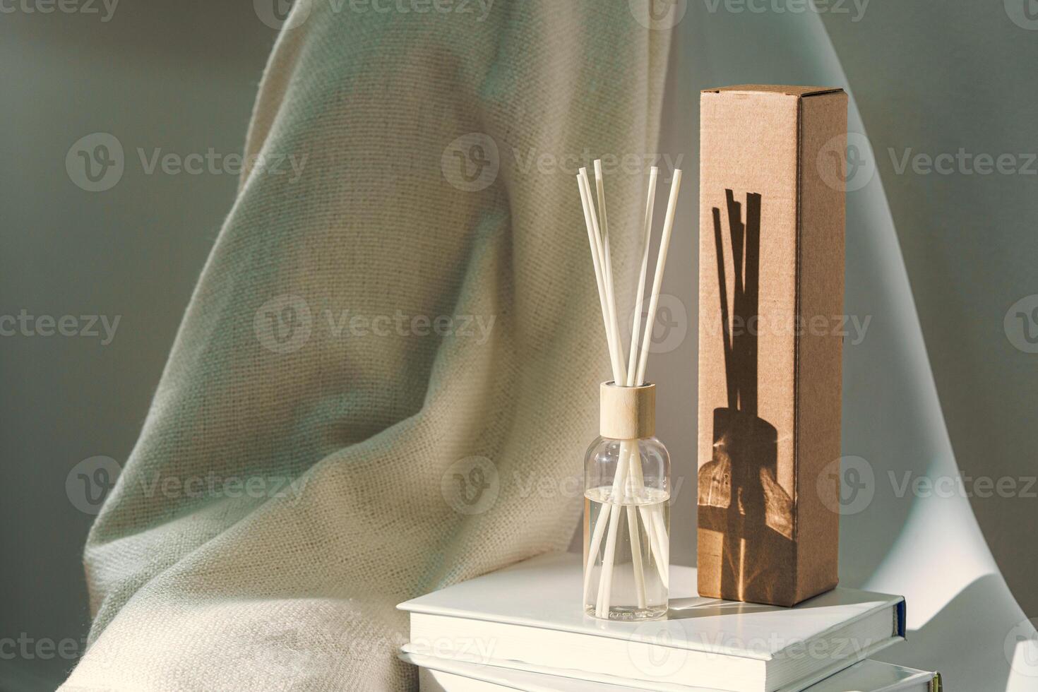Liquid home perfume in glass diffuser with sticks on chair photo