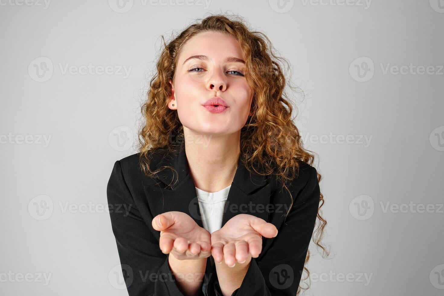 Young Woman Blowing a Kiss Towards the Camera in a Studio Setting photo
