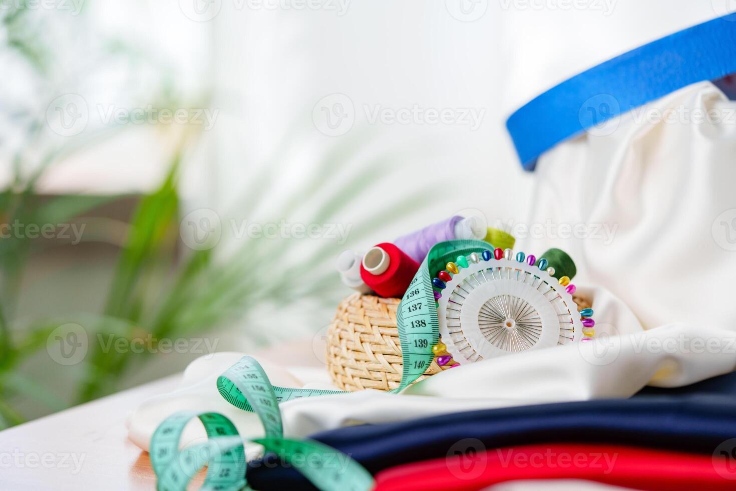 Crafting supplies arranged on a wooden table with colorful threads, measuring tape, and fabric in a well-lit workspace photo