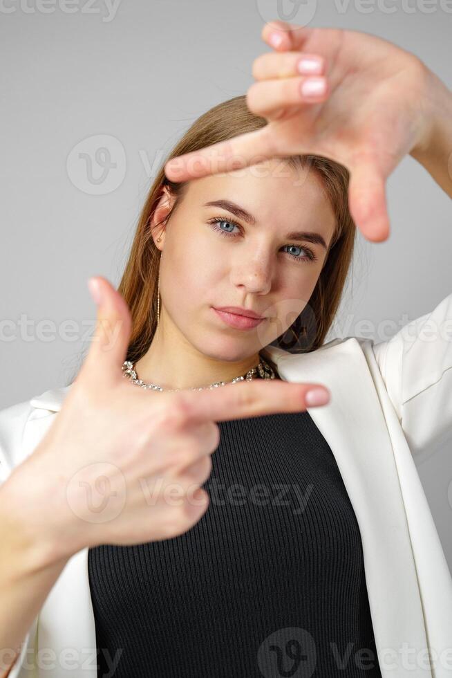 Young Woman Making Frame Gesture With Hands Against a Neutral Background photo