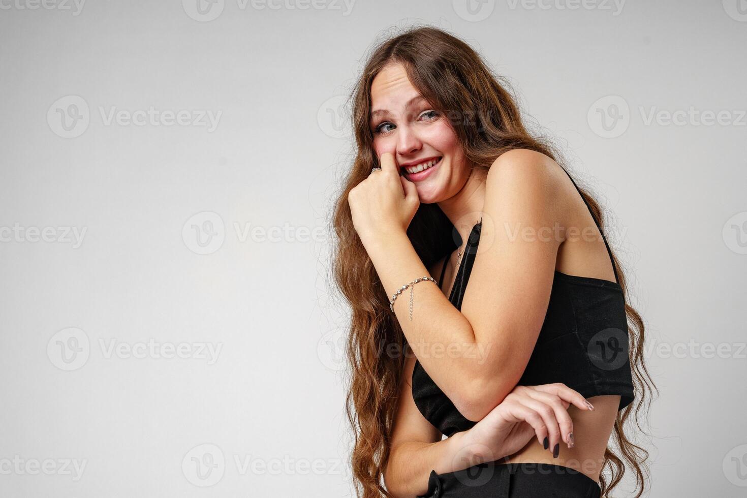Smiling Young Woman Posing in a Black Top Against a Grey Background photo