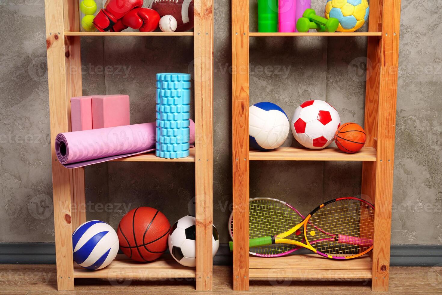 Shelves with different sports equipment against green wall photo