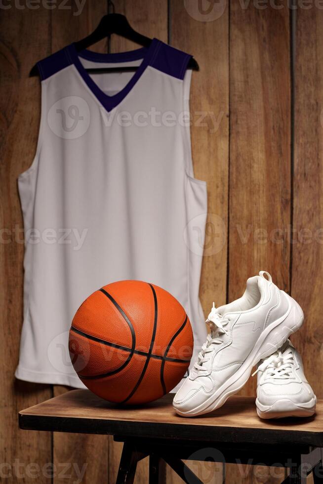 White sneakers and basketball ball against wooden background photo