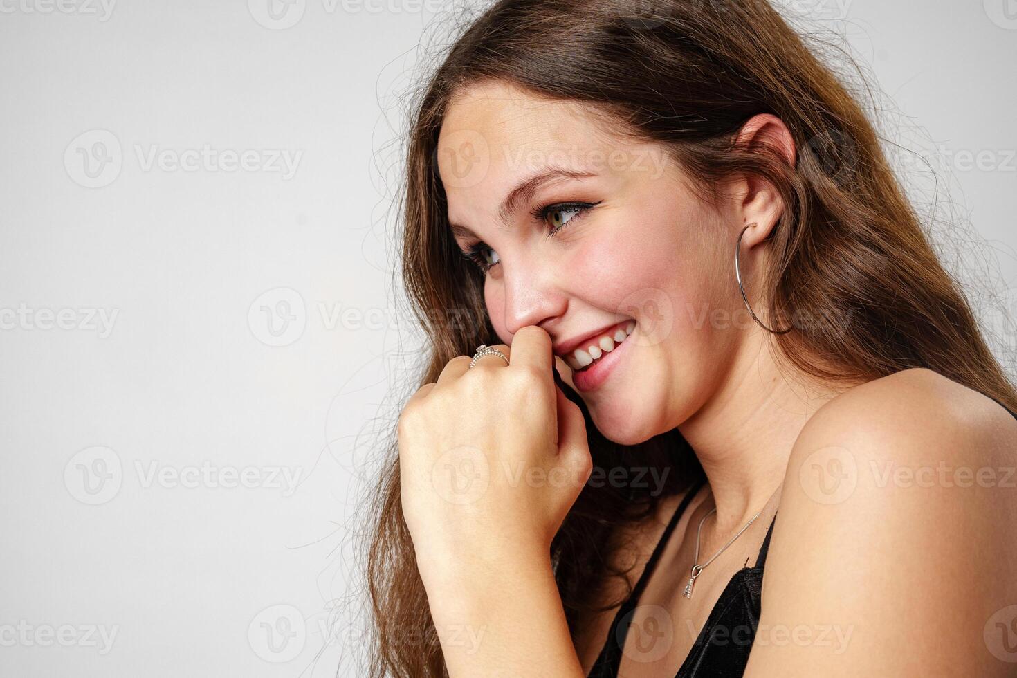 Smiling Young Woman Posing in a Black Top Against a Grey Background photo