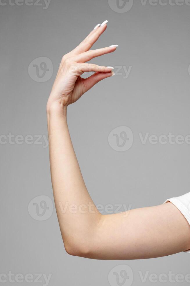 Female hand gesturing sign against gray background photo