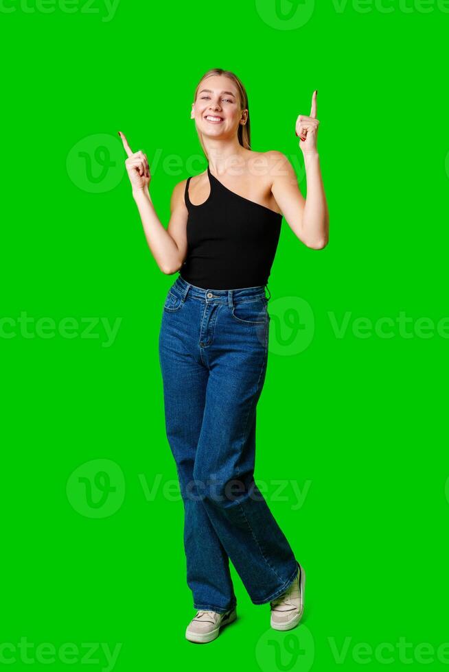 Young Woman Pointing Up Against Green Background photo