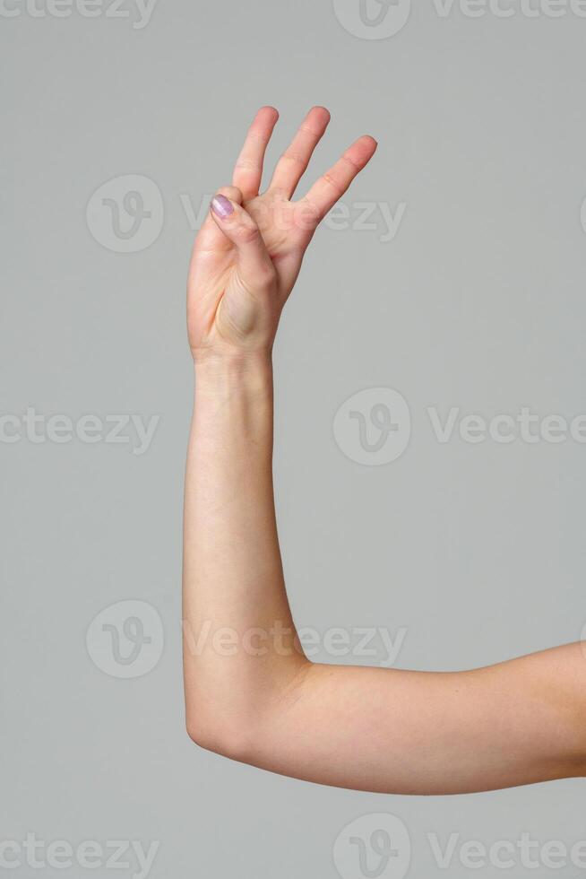 Female hand gesturing numbers on gray background photo