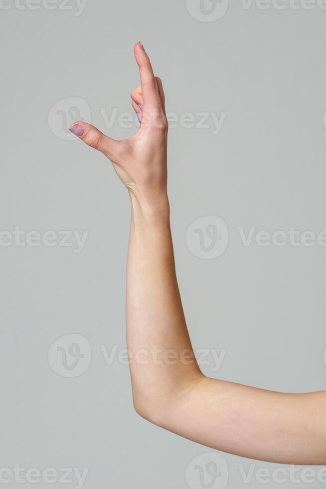Female hand sign against gray background in studio photo