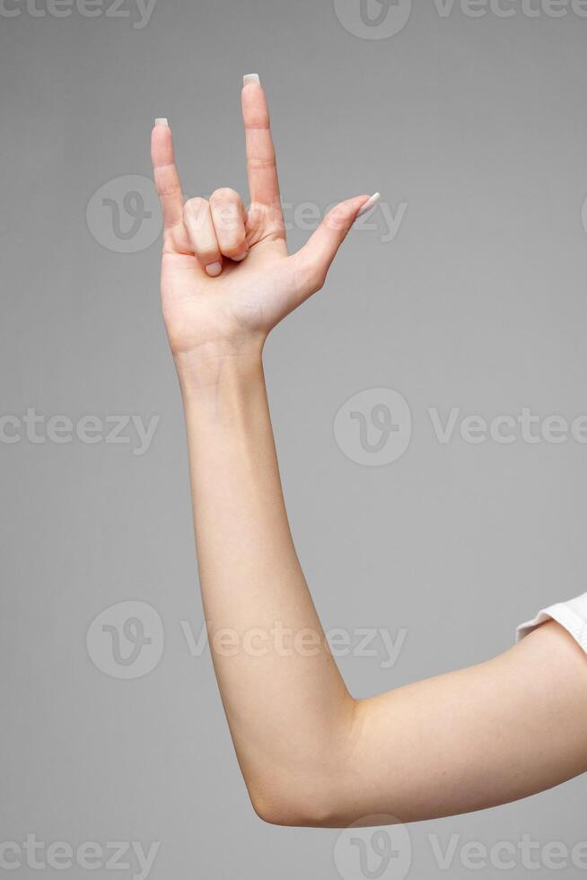 Female hand gesturing sign against gray background photo