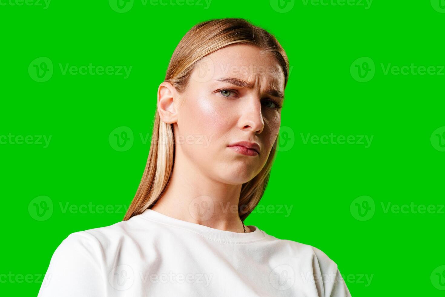 Young Woman With Pursed Lips Expressing Skepticism Against Green Screen Background photo
