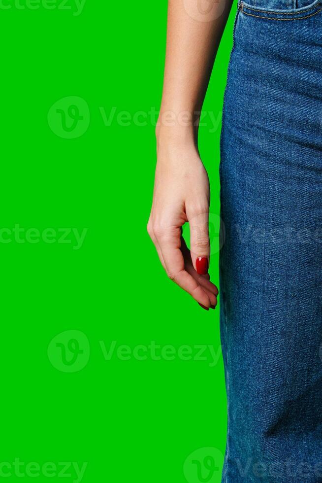 Woman Standing Sideways Wearing Denim Jeans Against a Green Background photo