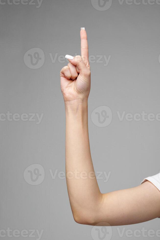 Female hand gesturing sign against gray background photo