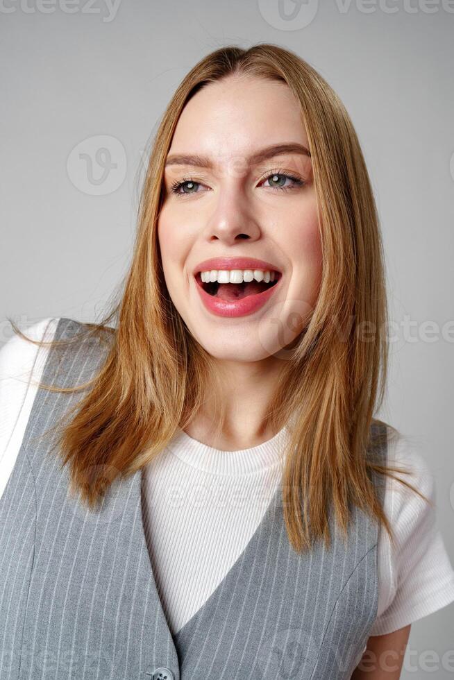 Joyful Young Blonde Woman Smiling against gray background photo