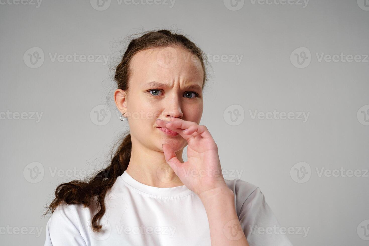 Young Woman Making Funny Face With Her Fingers on gray background photo