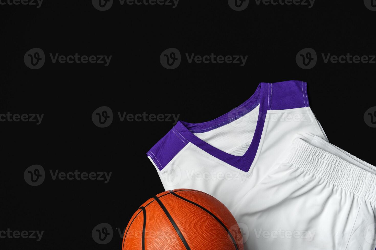 Close-Up of Basketball and White and Purple Jersey on a Black Background photo