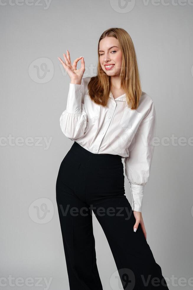 Young Woman Gesturing OK Sign With Hand Against a Neutral Background photo