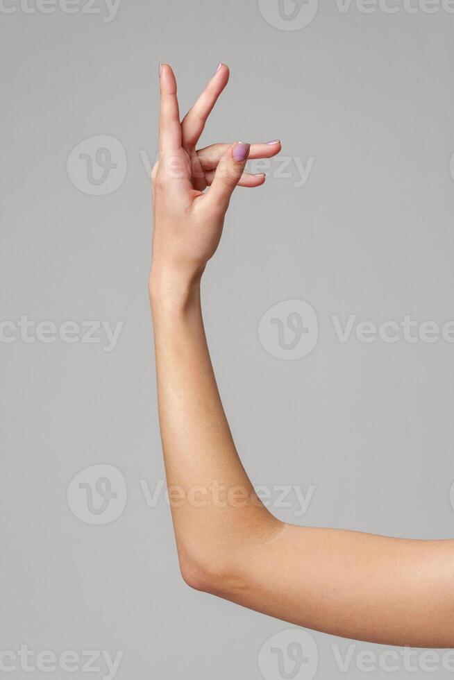 Female hand sign against gray background in studio photo