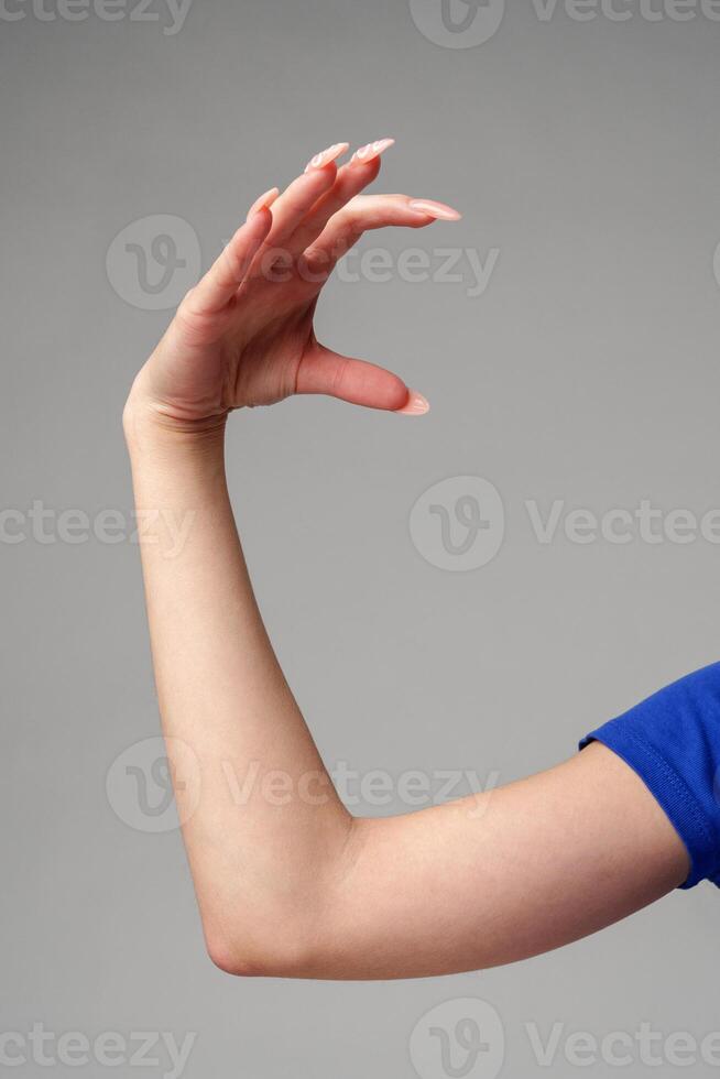 Female hand sign against gray background in studio photo