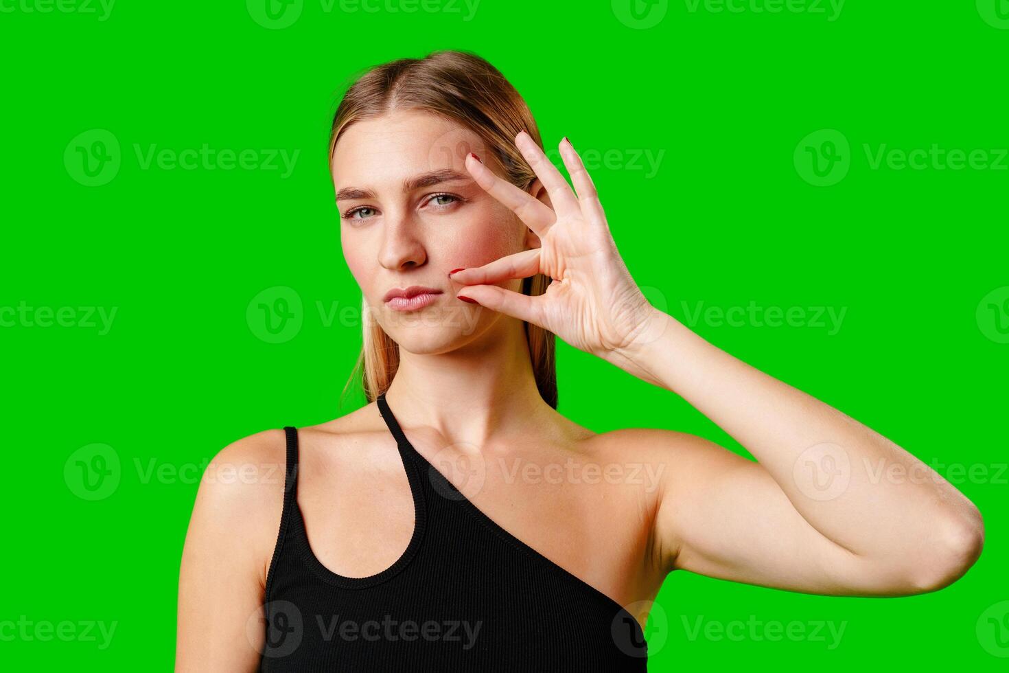Young Woman Gesturing Silence With Finger on Lips Against Green Screen Background photo