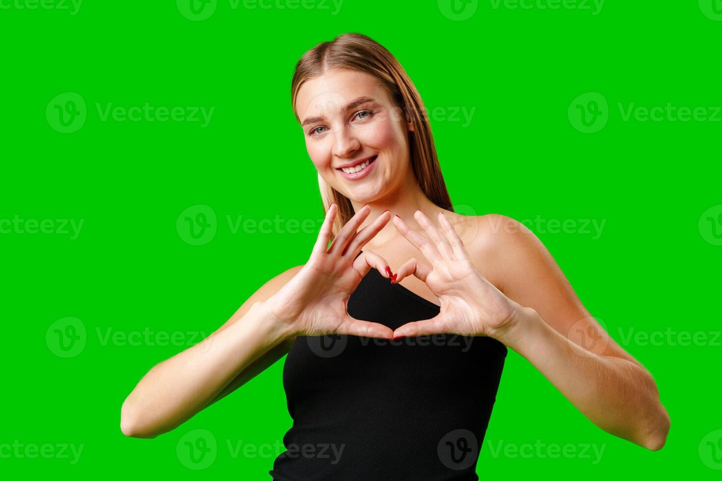 Young Woman Making Heart With Hands on green background photo