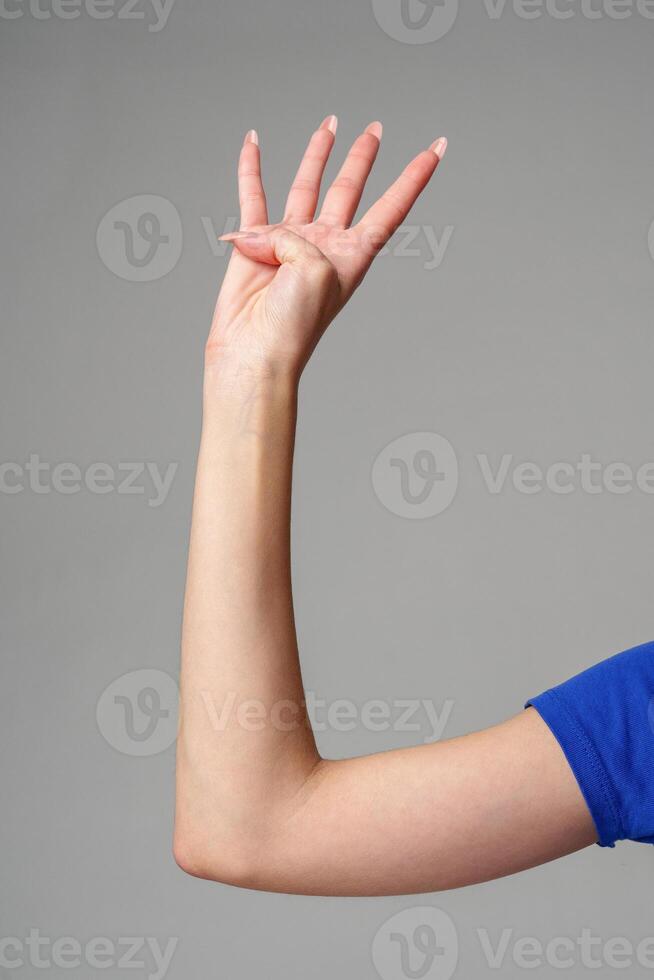 Female hand sign against gray background in studio photo