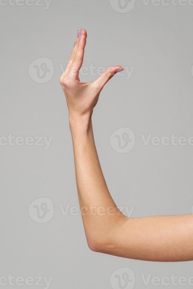 Female hand sign against gray background in studio photo