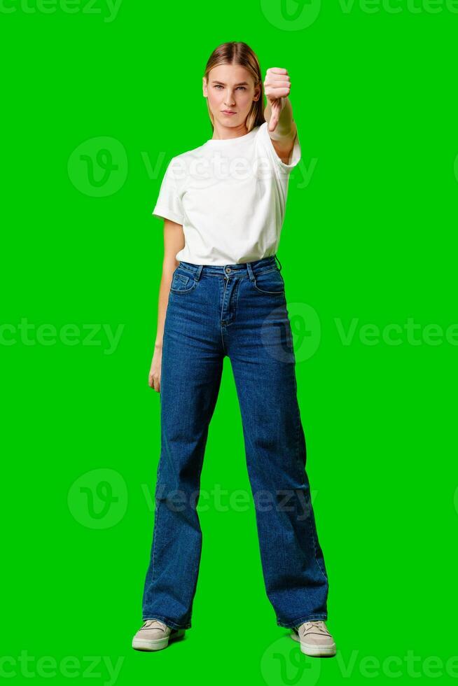 Young Woman Expressing Disapproval With a Thumbs Down Gesture Against a Green Background photo