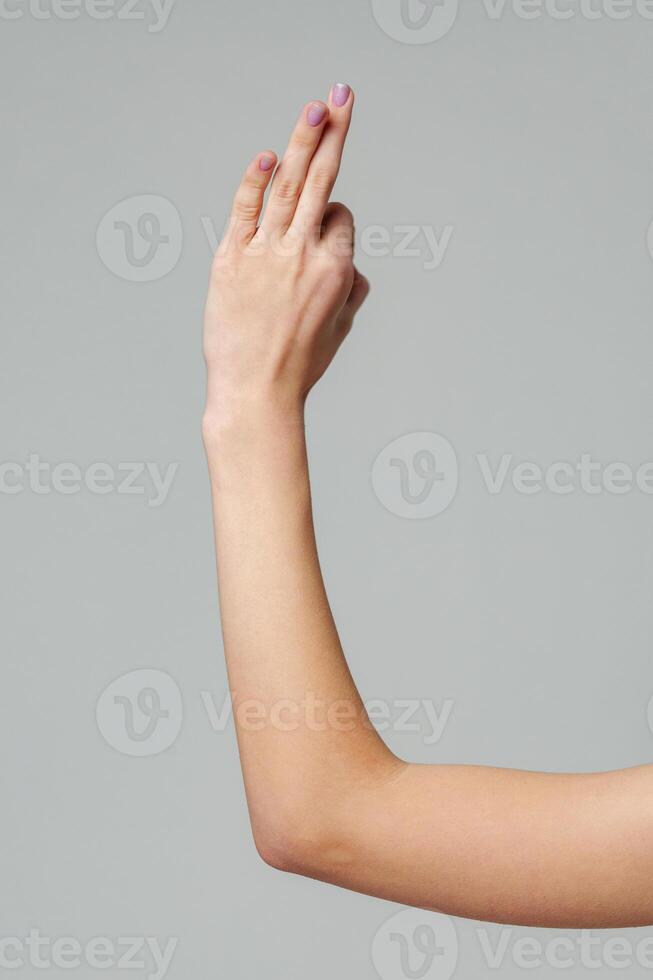 Female hand sign against gray background in studio photo