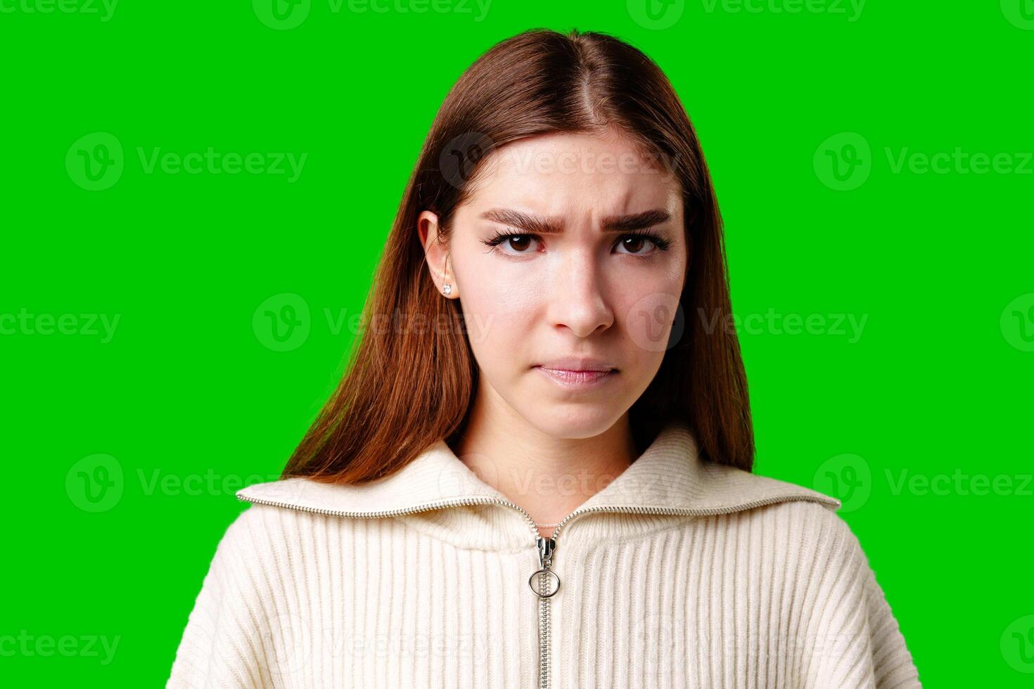 Young Woman With a Puzzled Expression Standing Against a Bright Green Background photo