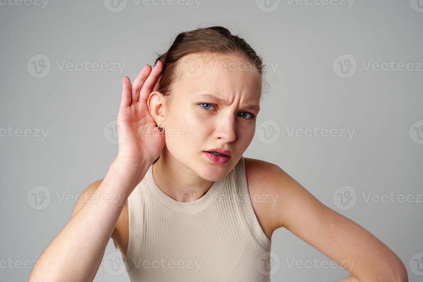 Young Woman Holding Her Ear With Her Hands on gray background photo