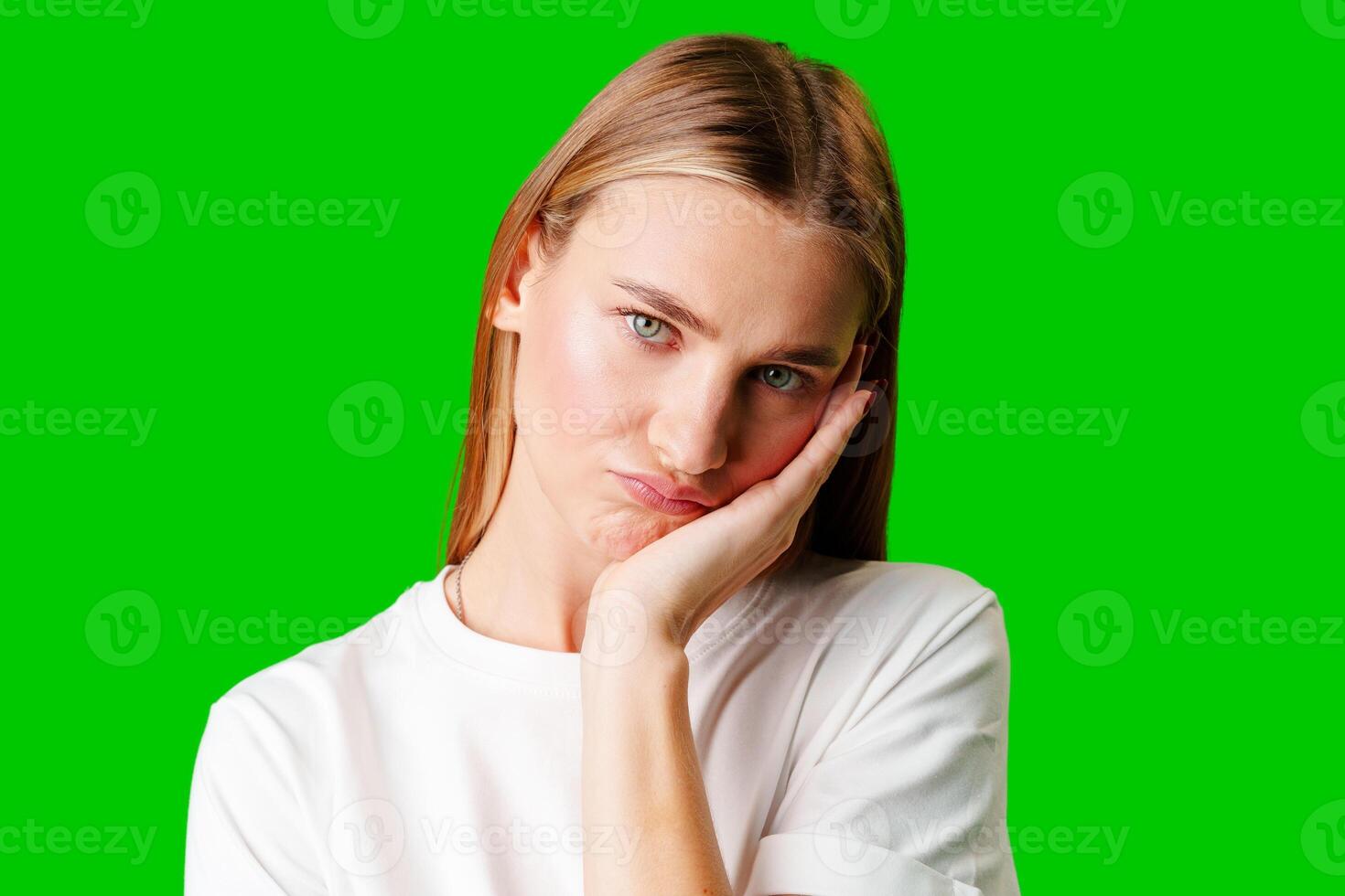 Young Woman With Pursed Lips Expressing Skepticism Against Green Screen Background photo